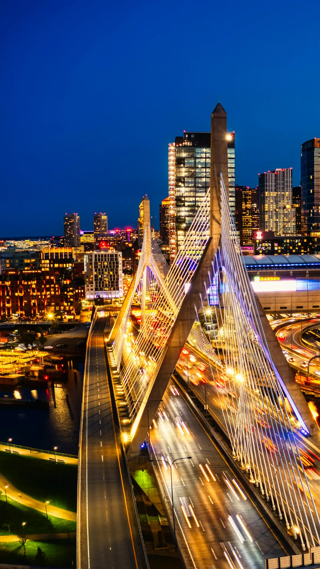 Zakim Bridge iluminada à noite com o skyline de Boston ao fundo